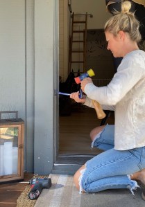 A woman is using a hammer and prybar to remove door trim